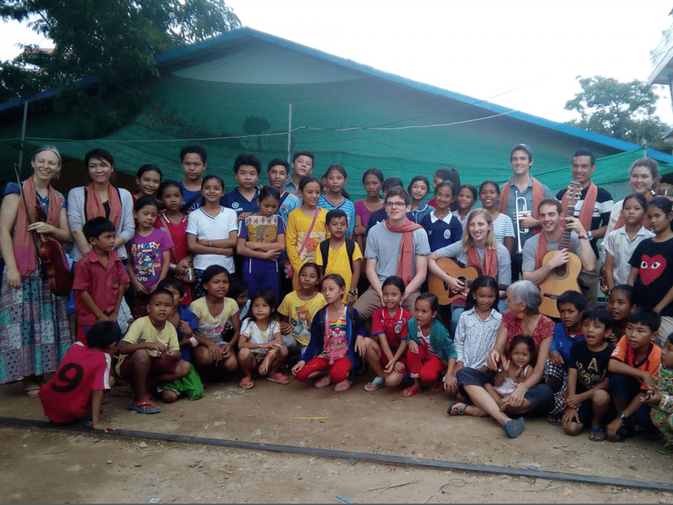 Volunteers with guitars and a large group of children outside a partner NGO
